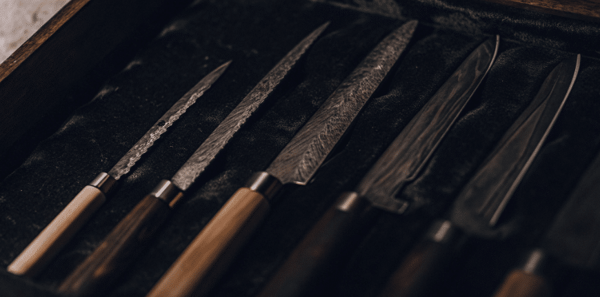 Materials and Build Quality - Japanes Knives Tips The image showcases a collection of sujihiki knives, featuring narrow blades made from high carbon stainless steel, known for their razor sharp edges and precision in slicing. The knives are displayed with wooden or pakkawood handles, emphasizing their balance and craftsmanship, ideal for professional chefs and home cooks alike.
