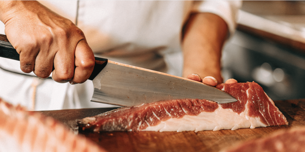 The image showcases a honesuki knife, featuring a triangular shaped blade with a thick spine and sharp tip, ideal for breaking down poultry and making precise cuts around bones and joints. Its rigid design and large heel enhance the knife's ability to apply force for tasks like de-boning, making it a preferred choice for both home cooks and chefs.