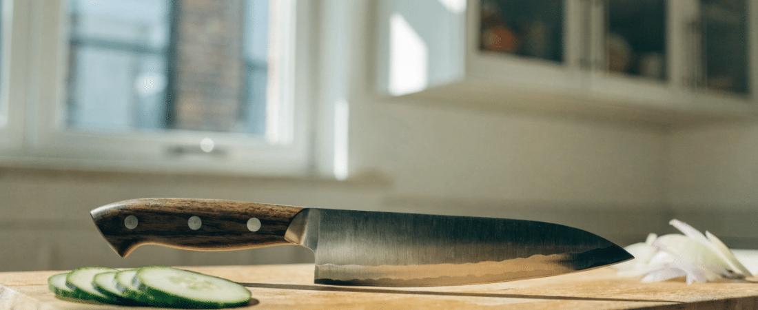 Premium Japanese Knive - Japanes Knives Tips An editorial style photo of a premium Japanese kitchen knife on a clean wooden cutting board in a bright home kitchen, natural window light, sliced vegetables nearby, sharp blade detail, minimal styling, high-end food blog look, horizontal composition